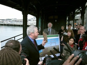 Mayor McGinn holds up a sample of the rotting wood that supports the seawall as it is now.  Photo by Darren  Dencklau